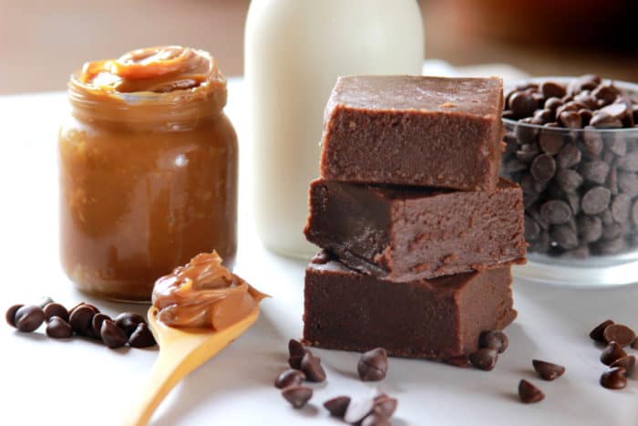 pieces of dulce de leche fudge, a jar with dulce de leche, a bottle of milk, a little glass container with chocolate chips