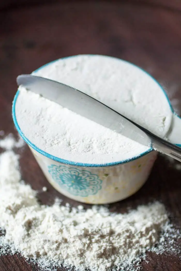 Flour in a white and light blue measuring cup.