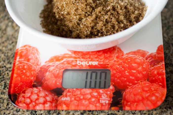 Kitchen scale with a white bowl with brown sugar on top. 