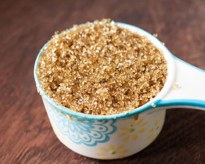 Brown sugar in a white and light blue measuring cup.