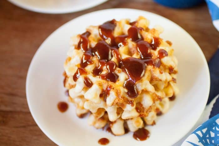 cheese waffles with guava jam on top. On a white plate