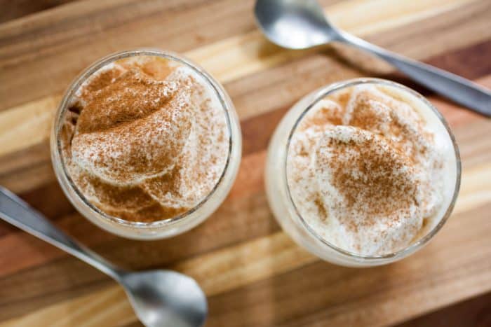 2 glasses filled with custard and topped with meringues.