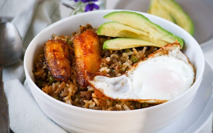 fried rice in a bowl with plantain, fried egg, and avocado