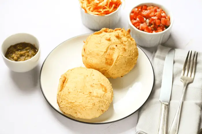 2 Bolivian stuffed potatoes on a plate with different sauces around it