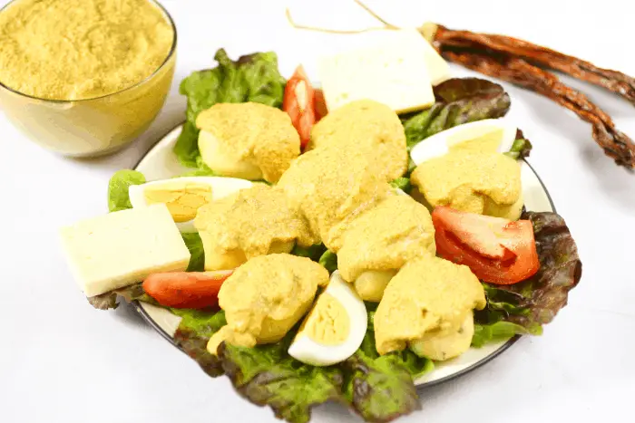 plate with lettuce, potatoes with spicy peanut sauce, slices of eggs, tomatoes, and olives