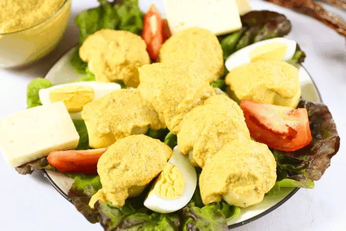 plate with lettuce, potatoes with spicy peanut sauce, slices of eggs, tomatoes, and olives