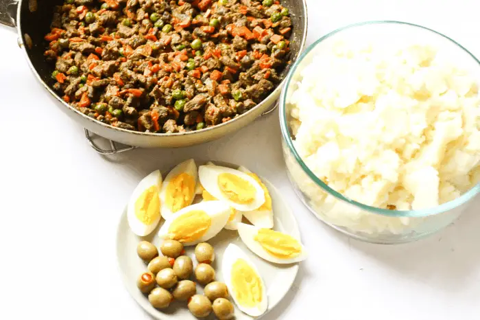 plate with olives and eggs, bowl with mashed potatoes, pan with meat and vegetables