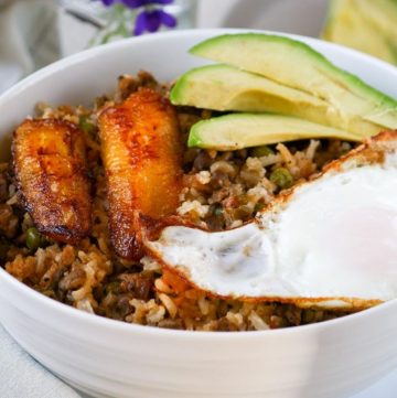 fried rice in a bowl with plantain, fried egg, and avocado