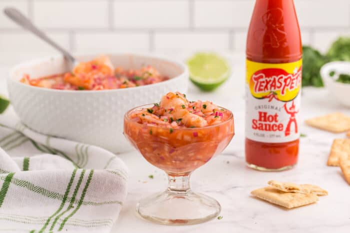 small glass with ceviche, a jar of Texas Pete hot sauce