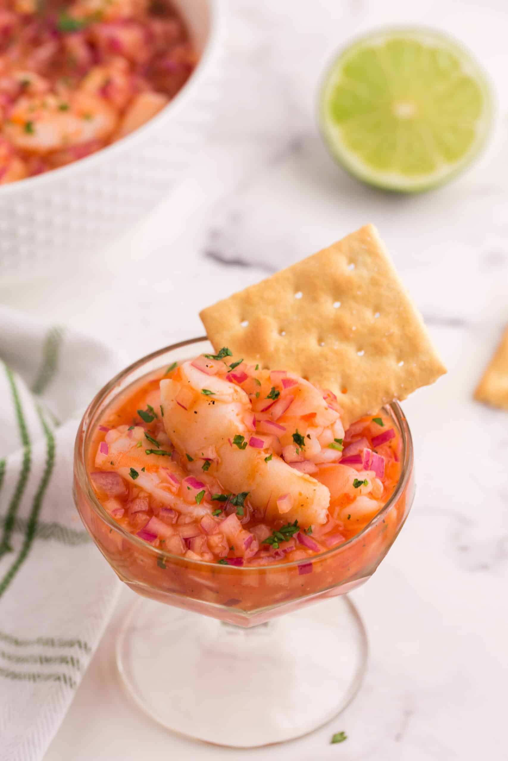 Shrimp ceviche in small glass with a cracker.