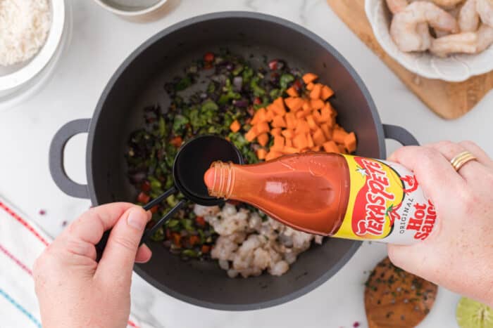 adding hot sauce to the pot