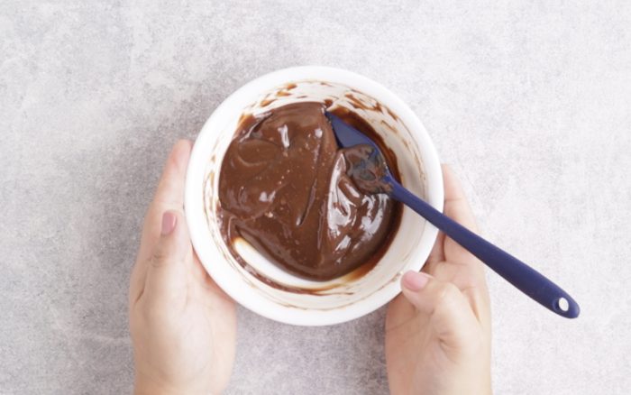 manos agarrando bowl con chocolate derretido.