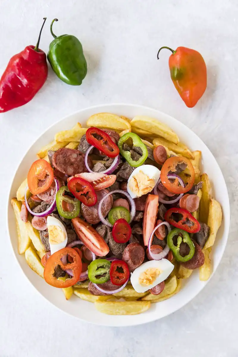 plato blanco con papas, chorizos, carnes, huevos, tomates, cebollas